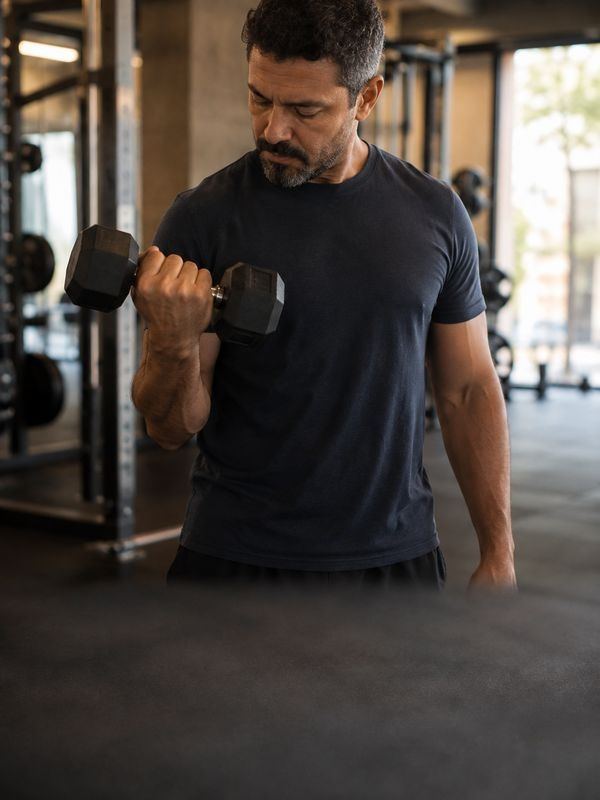 Homem treinando com halteres em academia